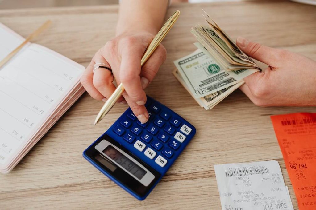 woman handling money and using calculator
